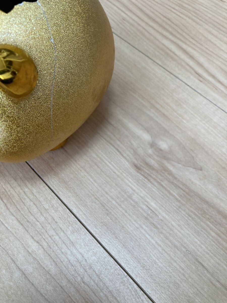 「写真の説明」地震で床に落ちて割れた金色の豚の貯金箱